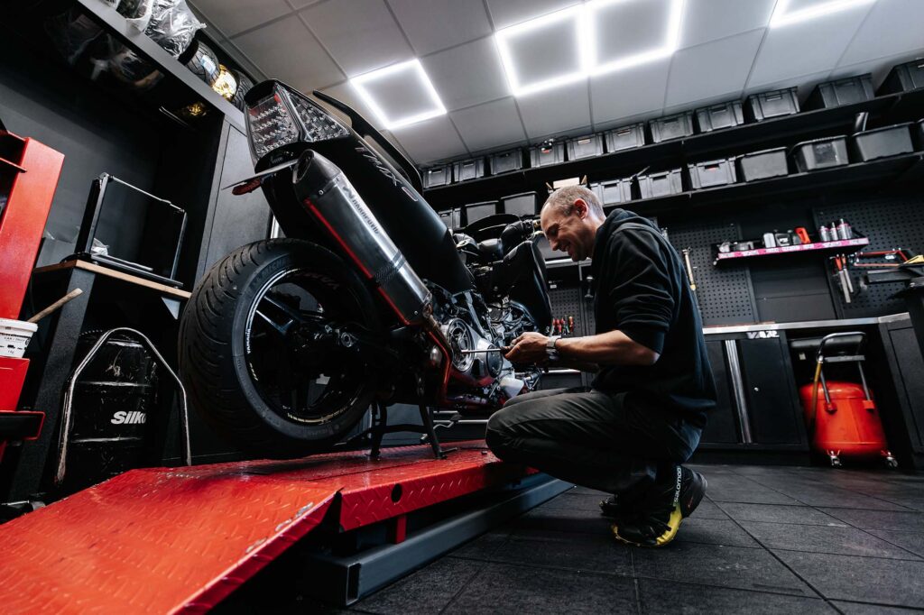 Photo d'une personne entrain de réparer une moto - John 2 Roues magasin de motos à Doussard